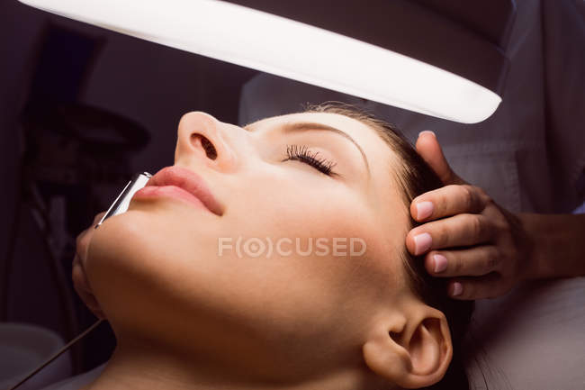 Крупним планом дерматолог, який проводить лазерну епіляцію на обличчі пацієнта в клініці — стокове фото