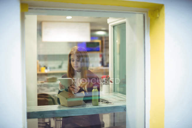 Mujer usando tableta digital mientras come ensalada en el restaurante - foto de stock