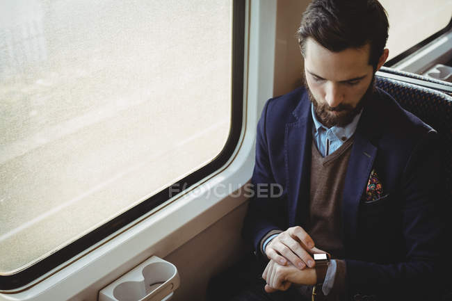 Бізнесмен перевіряє час на годиннику під час подорожі в поїзді — стокове фото