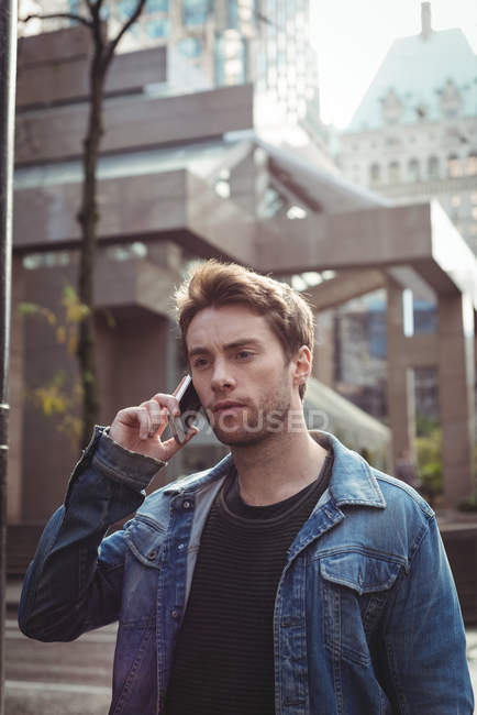 Человек разговаривает по мобильному телефону, стоя на улице — стоковое фото