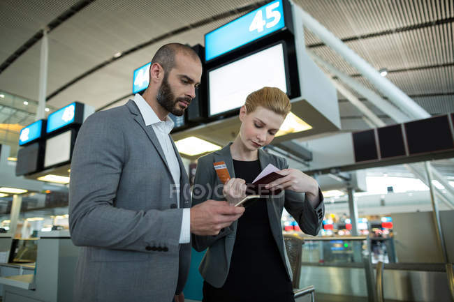 Ділові люди, які тримають посадковий талон і використовують мобільний телефон в терміналі аеропорту — стокове фото