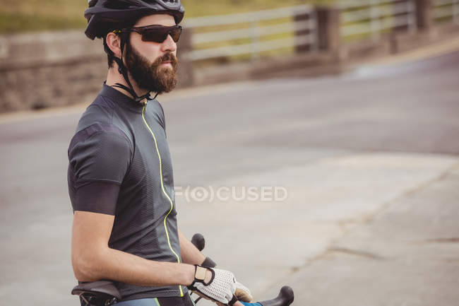 Спортсмен стоїть зі спортивним велосипедом на заміській дорозі — стокове фото