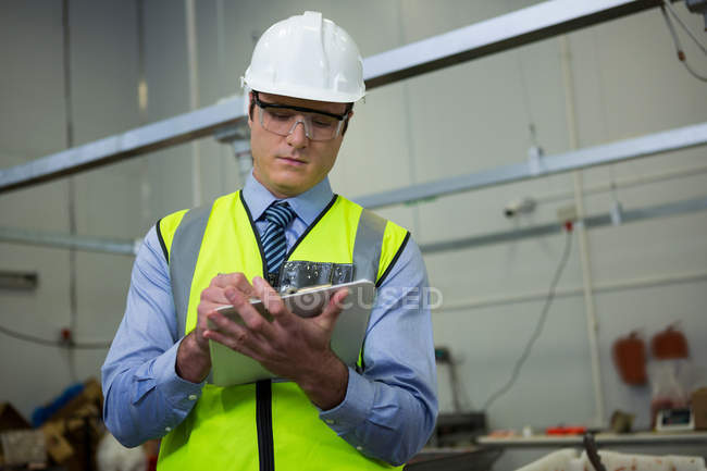 Technician writing on clipboard at industrial factory — Stock Photo