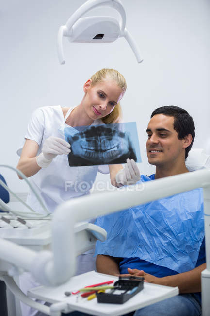 Dentist showing dental x-ray to patient at clinic — Stock Photo