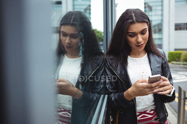 Mulher usando telefone celular fora do prédio de escritórios — Fotografia de Stock
