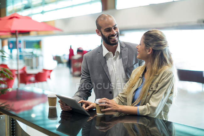 Couple souriant interagissant avec chacun ou en salle d'attente au terminal de l'aéroport — Photo de stock