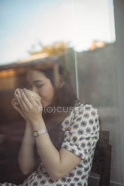 Женщина с чашкой кофе у окна в кафе — стоковое фото