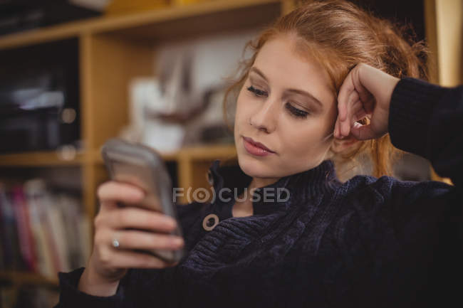 Nachdenkliche Frau nutzt Handy zu Hause — Stockfoto