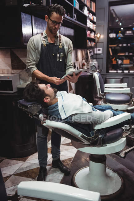 Barbier regarder style barbe sur tablette numérique dans le salon de coiffure — Photo de stock