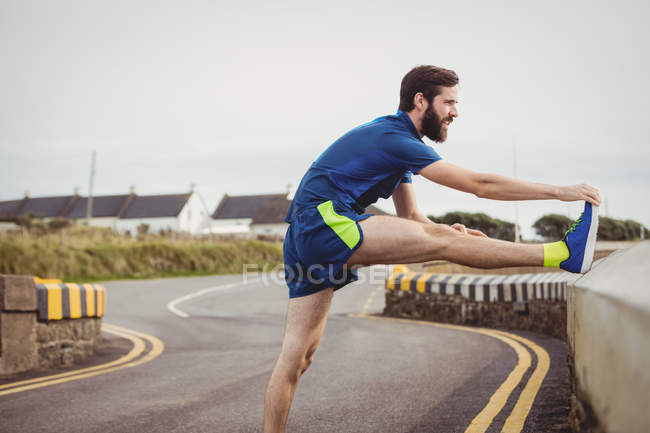 Schöner Athlet streckt sein Bein auf der Straße aus — Stockfoto