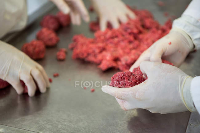 Sección media de carniceros que preparan bolas de carne en la fábrica de carne - foto de stock