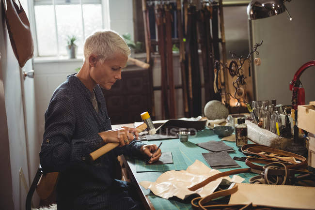 Reife Handwerkerin hämmert in Werkstatt auf Leder — Stockfoto