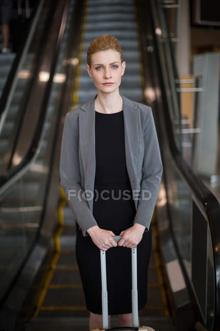 Бізнес-леді стоячи біля ескалатора з багажу в аеропорту — стокове фото
