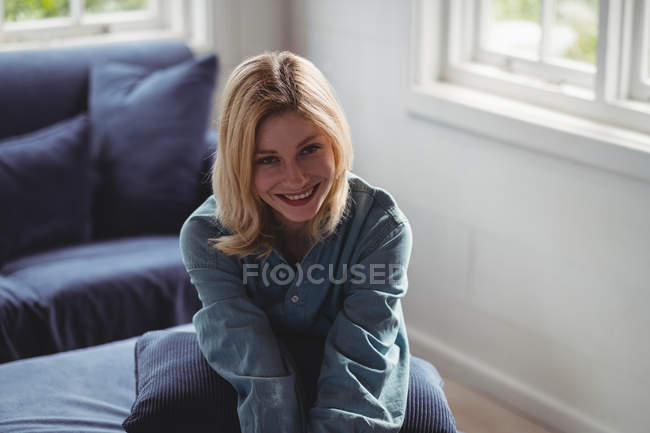 Retrato de mulher bonita sentada no sofá na sala de estar em casa — Fotografia de Stock