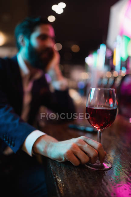 Бизнесмен держит бокал вина в баре — стоковое фото