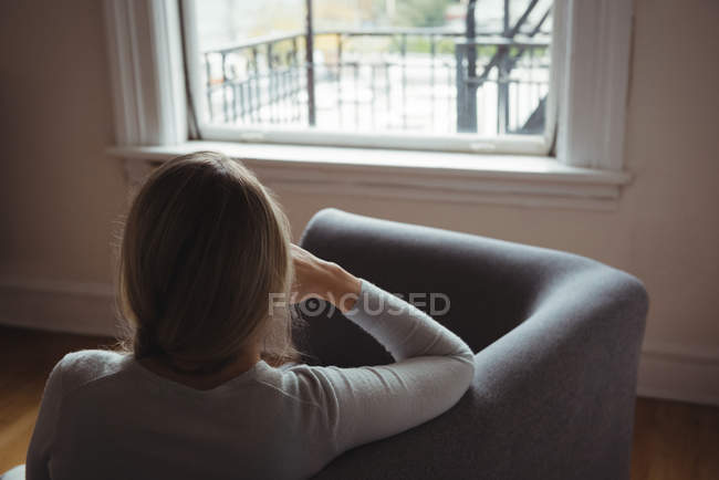 Вид сзади женщины, сидящей на диване в гостиной дома — стоковое фото