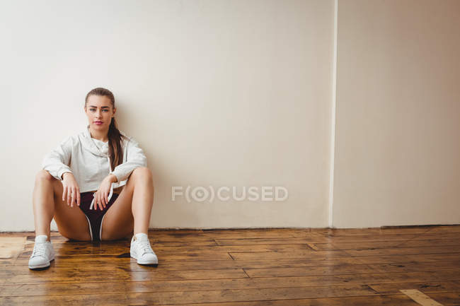 Молода випадкова жінка сидить на підлозі в танцювальній студії — стокове фото