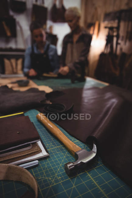 Pezzo di pelle e martello sul tavolo in officina — Foto stock