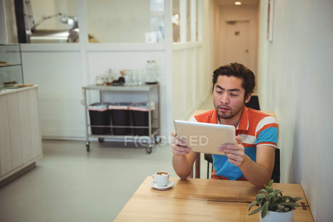 Man using digital tablet with coffee cup on table in coffee shop — Stock Photo