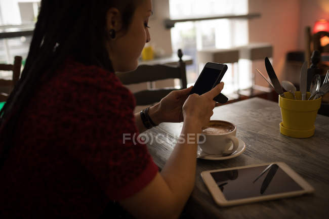 Hermosa mujer usando el teléfono móvil en la cafetería - foto de stock