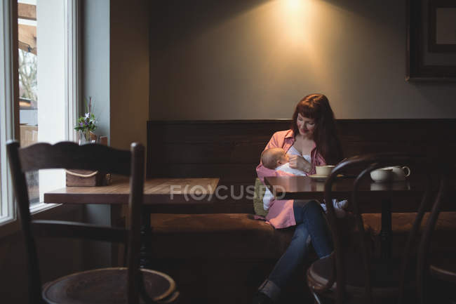 Mother breastfeeding infant baby in cafe interior — Stock Photo