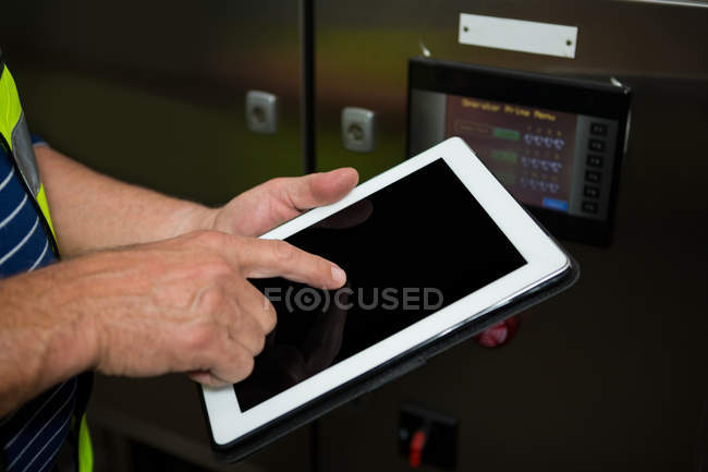 Sección media del empleado masculino usando tableta digital en fábrica - foto de stock