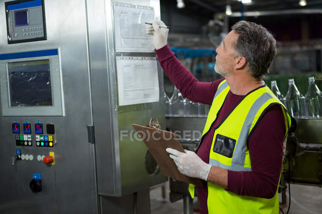 Trabajador manual senior analizando maquinaria en fábrica - foto de stock