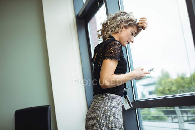 Donna d'affari sconvolta utilizzando il telefono cellulare in ufficio — Foto stock