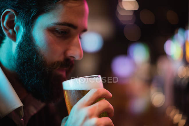 Primer plano del hombre tomando un vaso de cerveza en el bar - foto de stock
