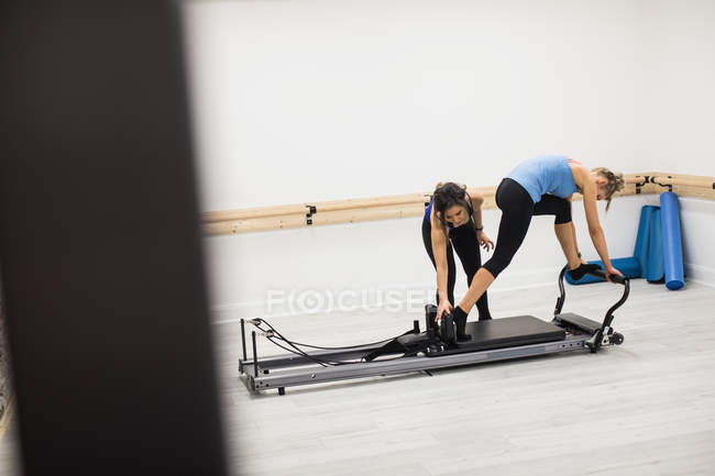 Trainerin unterstützt Frau bei Dehnübungen am Reformer im Fitnessstudio — Stockfoto
