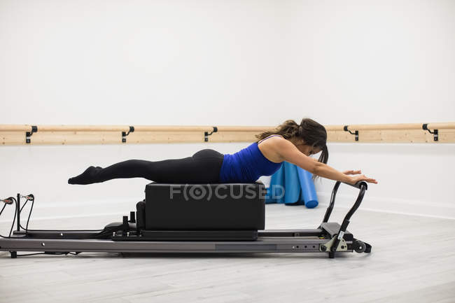 Mulher adulta média se exercitando no reformador no ginásio — Fotografia de Stock