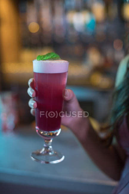 Mulher segurando um copo de coquetel rosa no bar — Fotografia de Stock