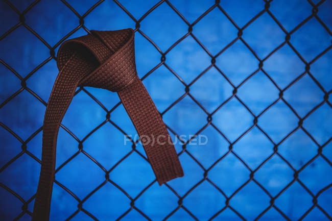 Gros plan de ceinture marron karaté accrochée à une clôture en treillis métallique dans un studio de fitness — Photo de stock