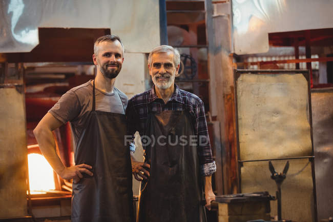 Портрет команды стеклодувов со скрещенными руками на стекольном заводе — стоковое фото