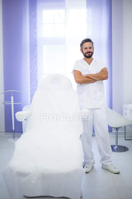 Портрет усміхненого лікаря, що стоїть з обіймами, схрещеними в клініці — стокове фото