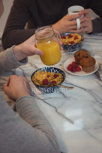 Vista ritagliata di due uomini che hanno succo di frutta e caffè a tavola — Foto stock