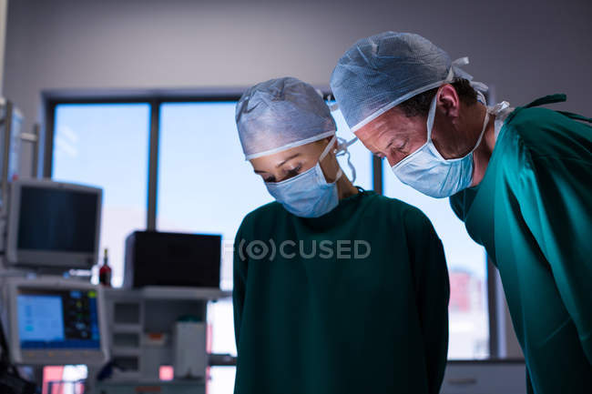 Cirurgiões masculinos e femininos realizando operação no teatro de operação do hospital — Fotografia de Stock
