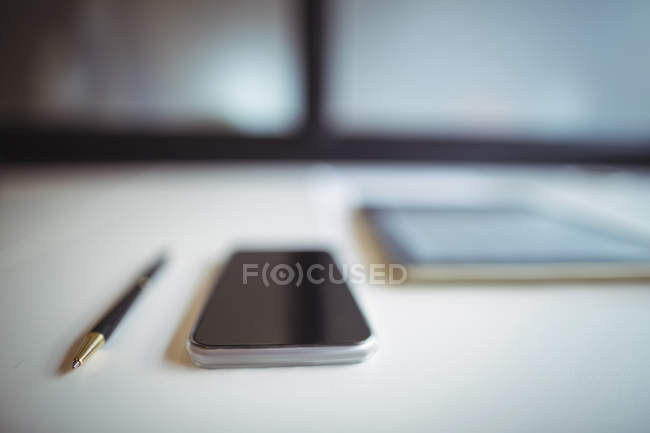 Крупный план цифрового планшета с мобильным телефоном и ручкой на офисном столе — стоковое фото