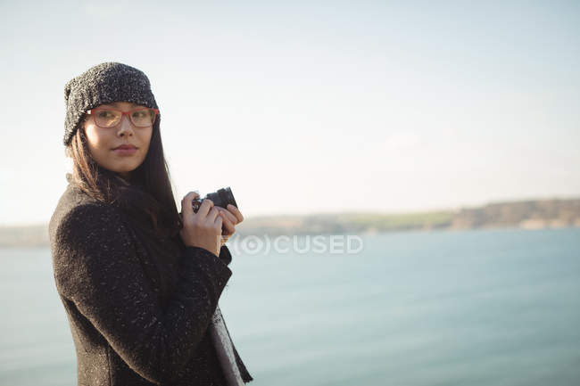 Женщина держит цифровую камеру возле озера в парке — стоковое фото