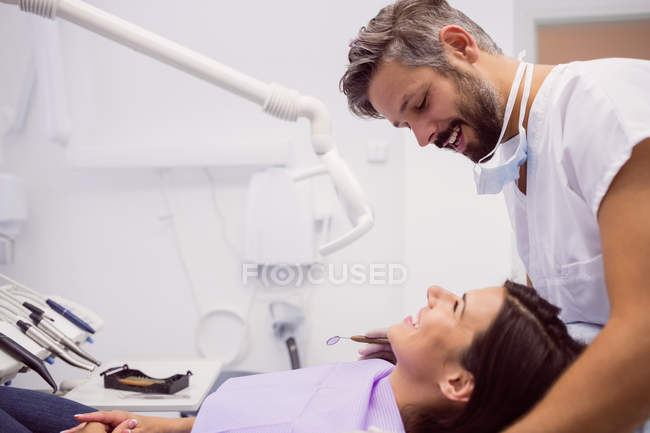 Zahnarzt lächelt, während er Patient in Klinik untersucht — Stockfoto