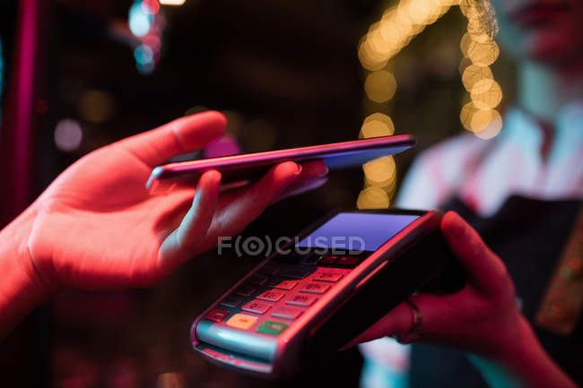 Customer making payment through smart phone in bar — Stock Photo