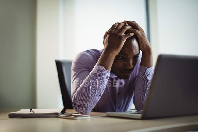 Разочарованный бизнес-руководитель работает на ноутбуке в офисе — стоковое фото
