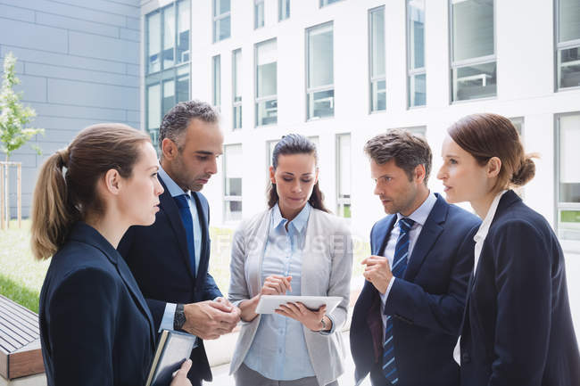 Business people discussing over digital tablet outside office building — Stock Photo