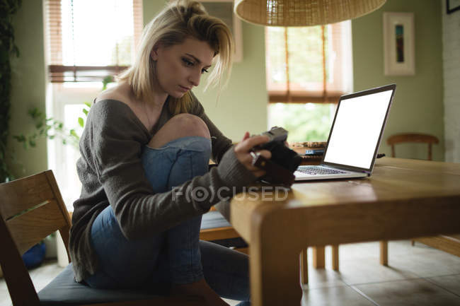 Mujer mirando fotos en cámara digital en la sala de estar en casa - foto de stock