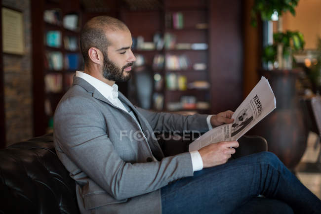 Empresario leyendo periódico en sala de espera en la terminal del aeropuerto - foto de stock