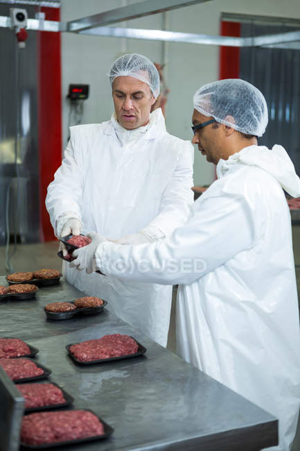 Два мясника упаковывают мясо на мясокомбинате — стоковое фото