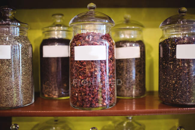 Différents pots d'épices disposés sur l'étagère dans la boutique — Photo de stock