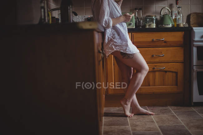 Жінка використовує мобільний телефон на кухні вдома — стокове фото