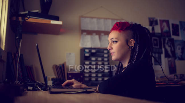 Женщина парикмахер с помощью ноутбука в магазине дредов — стоковое фото