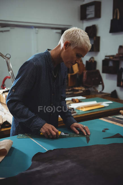 Attentive craftswoman working on a piece of leather in workshop — Stock Photo